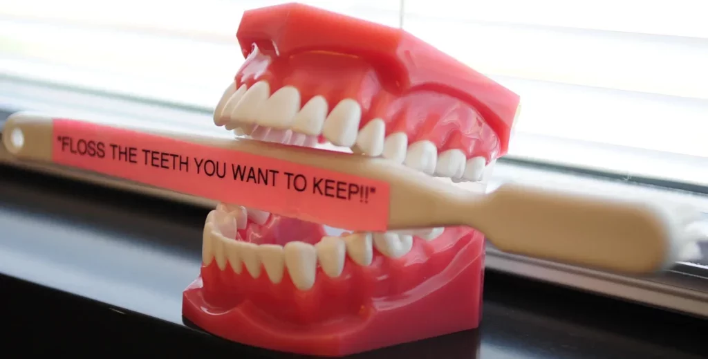 Dentures holding a toothbrush sign