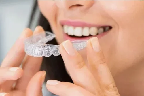 Woman putting in a pair of Invisalign braces, or clear aligners.