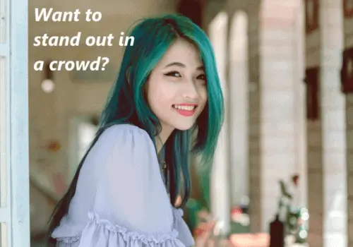 A young woman, with green hair, looking out a window, smiling with the text: want to stand out in a crowd?