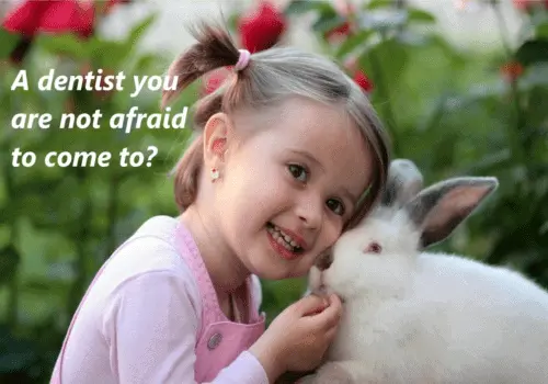A young, smiling girl is nuzzling a white haired rabbit, surrounded by flowers, with the text: A dentist you are not afraid to come to?